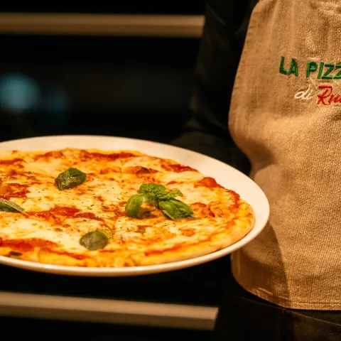 Pizza Margherita auf einem Teller vor einer Schürze mit Logo von La Pizza di Russillo