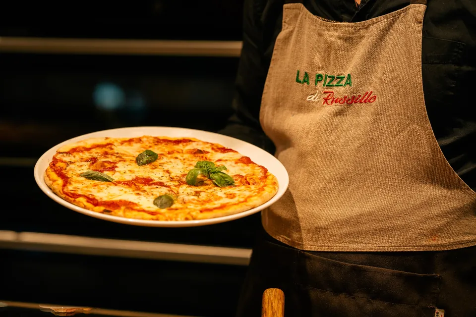 Pizza Margherita, serviert vor einer Schürze mit dem Schriftzug „La Pizza di Russillo“
