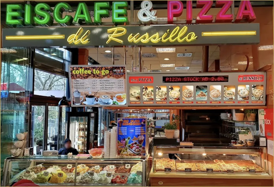 Leuchtschrift „Eiscafé & Pizza di Russillo“ über der Theke